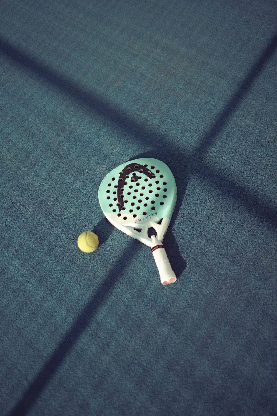 Padel rackets and a ball resting on the court