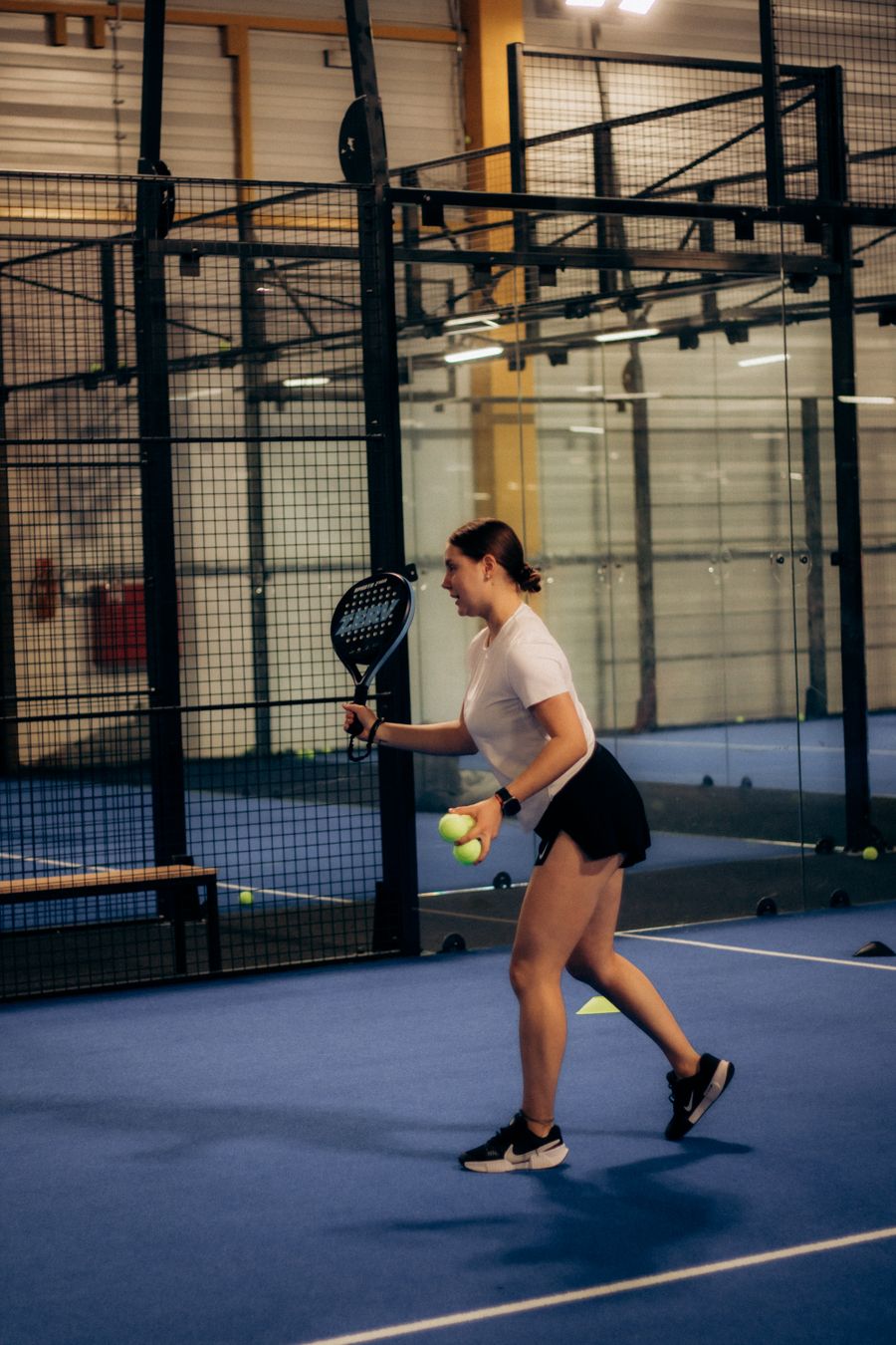 A padel player mid-rally on an indoor court