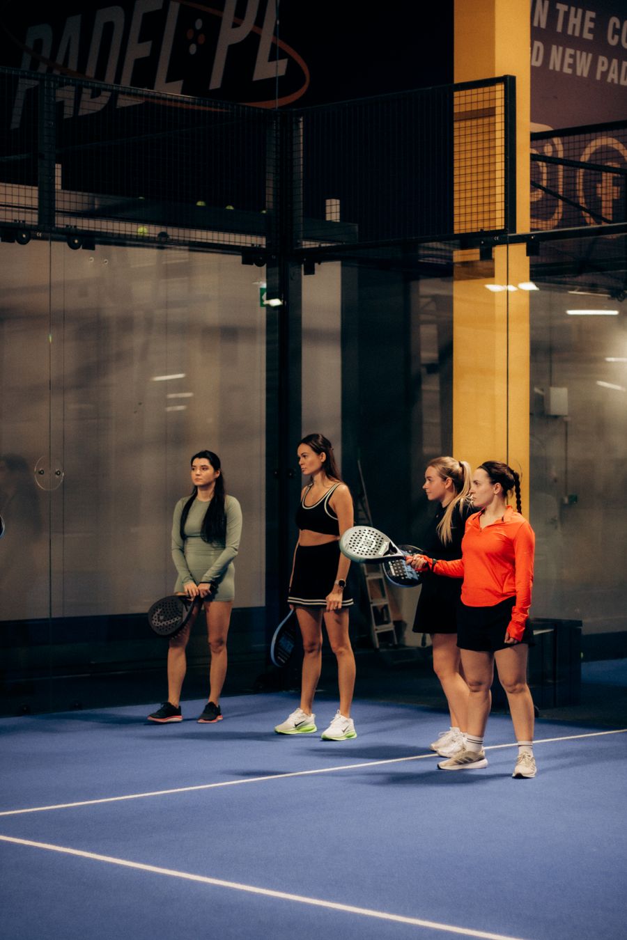 A group of padel players standing together and socialising courtside